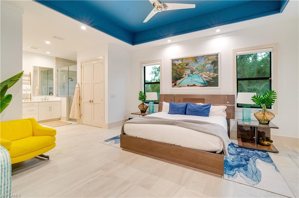 2991 2nd Street Northwest Naples, FL 34120 - Photo 17 of 43 a spacious bedroom with a bed a couch and potted plant with the outer view