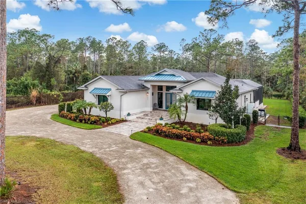 a view of a white house with a big yard and potted plants