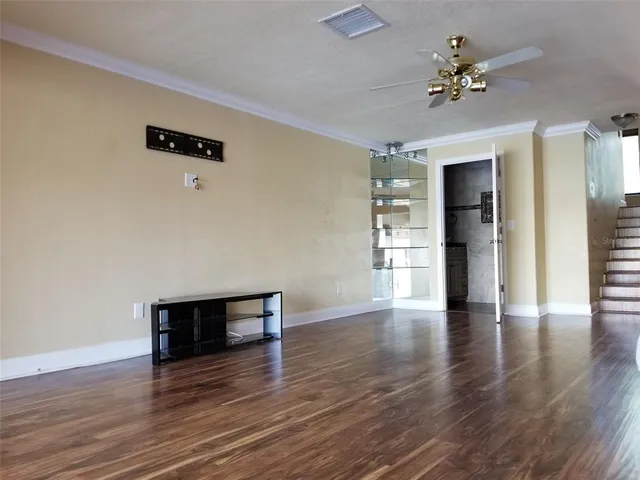 an empty room with wooden floor and a ceiling fan
