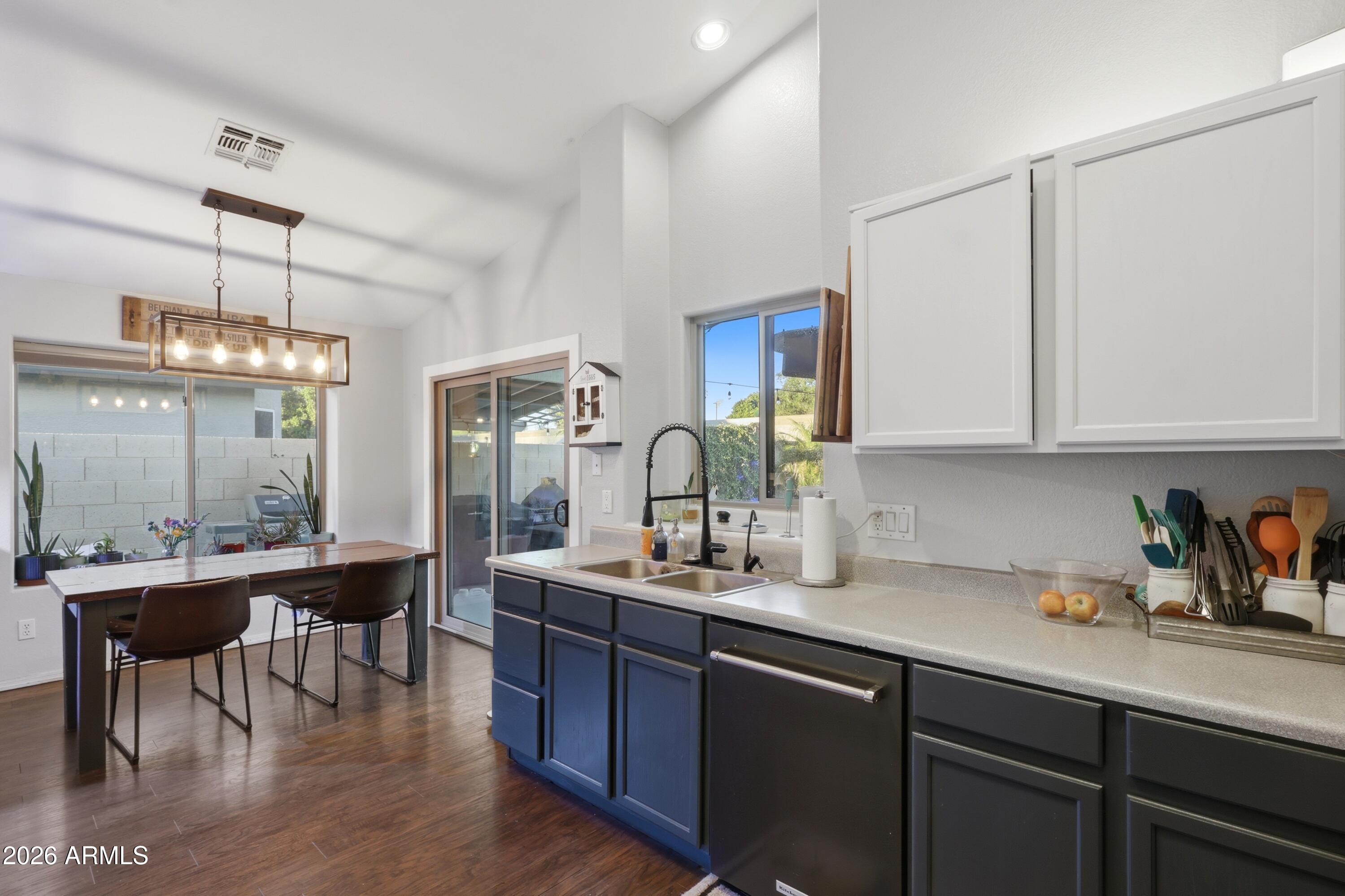 661 North Joshua Tree Lane Gilbert, AZ 85234 - Photo 10 of 47 a kitchen with stainless steel appliances kitchen island granite countertop a table chairs in it and wooden floors