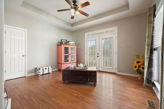 a bedroom with a bed and a large window with wooden floor