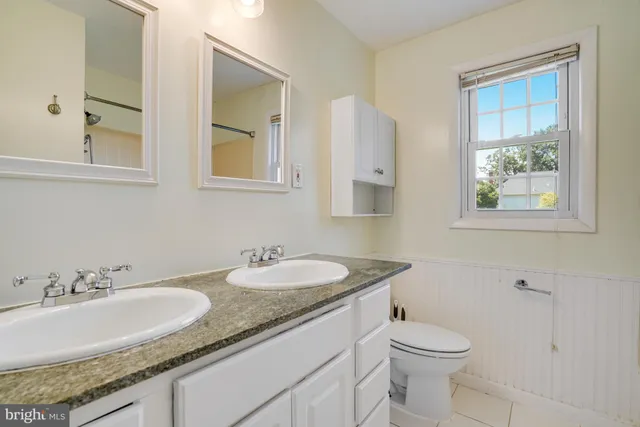 a bathroom with a granite countertop sink and a toilet