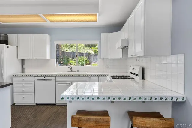 a kitchen with granite countertop white cabinets and white appliances