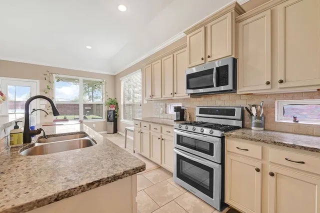 a kitchen with stainless steel appliances granite countertop a stove a sink and a microwave