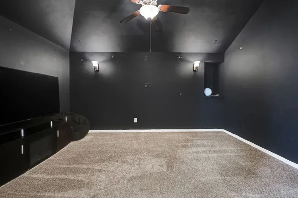 a view of an empty room with a chandelier fan