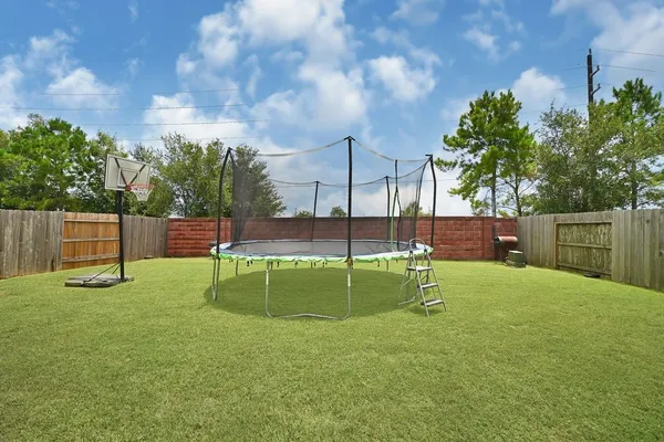 a view of a white house with a small yard and large trees