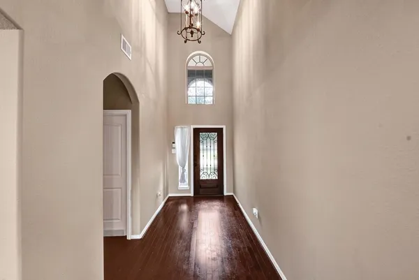a view of a hallway with wooden floor and a chandelier