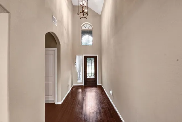 a view of a hallway with wooden floor and a chandelier