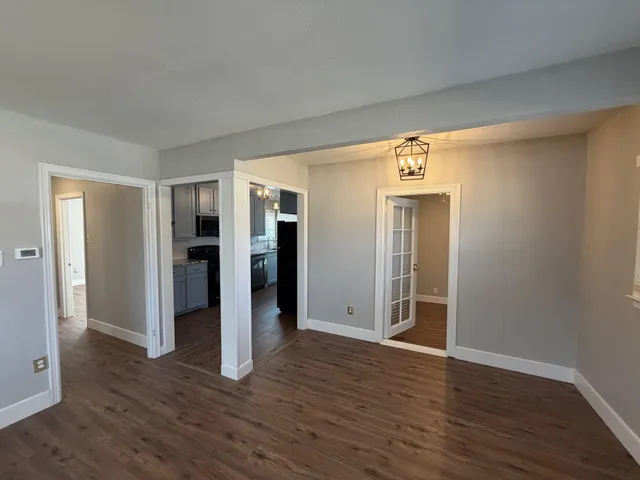 a view of an empty room with wooden floor and closet area