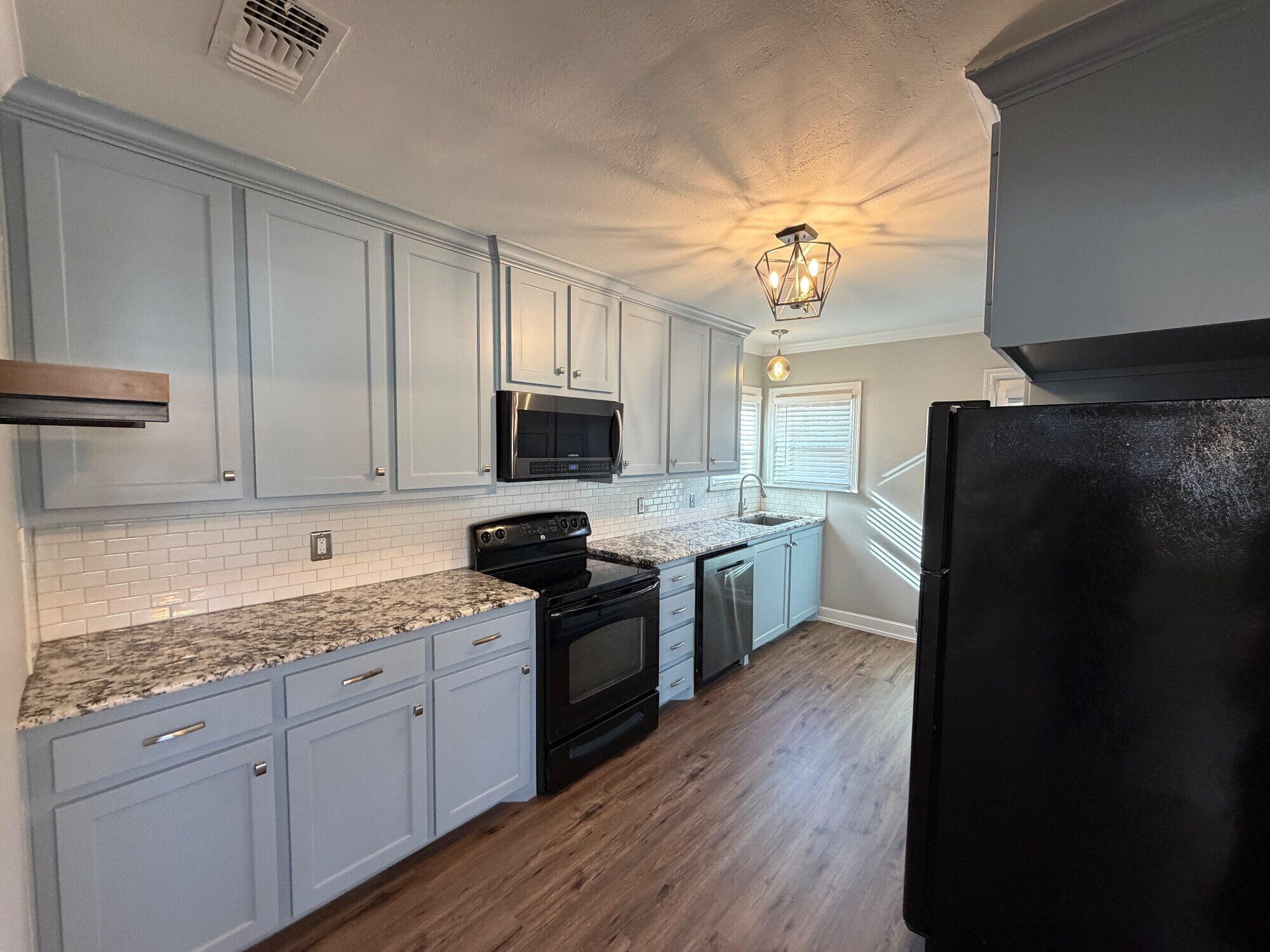 2703 30th Street Lubbock, TX 79410 - Photo 6 of 16 a kitchen with a sink dishwasher a refrigerator a stove and white cabinets with wooden floor