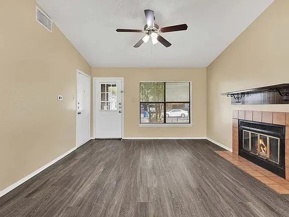 an empty room with windows fireplace and wooden floor