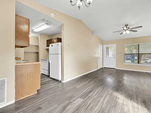 a view of a kitchen with wooden floor electronic appliances and windows