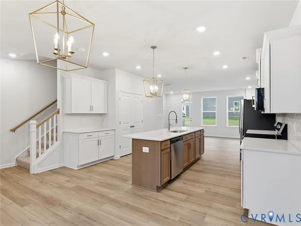 a large kitchen with kitchen island a stove a sink a center island and wooden floor