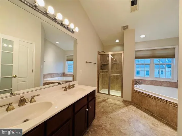 a bathroom with a tub double vanity sink and a mirror