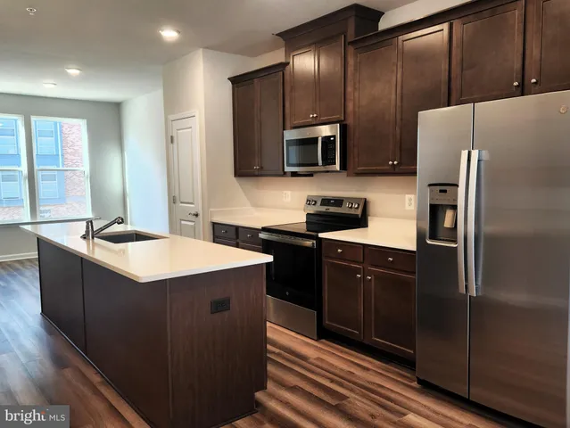 a kitchen with stainless steel appliances granite countertop a refrigerator a sink and wooden cabinets