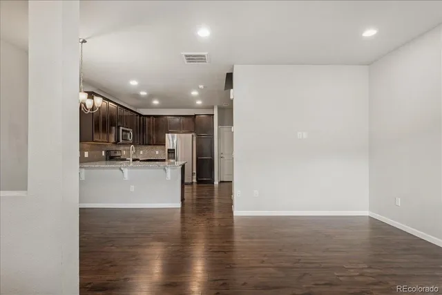 a kitchen with granite countertop stainless steel appliances a refrigerator a stove a sink cabinets and a wooden floor