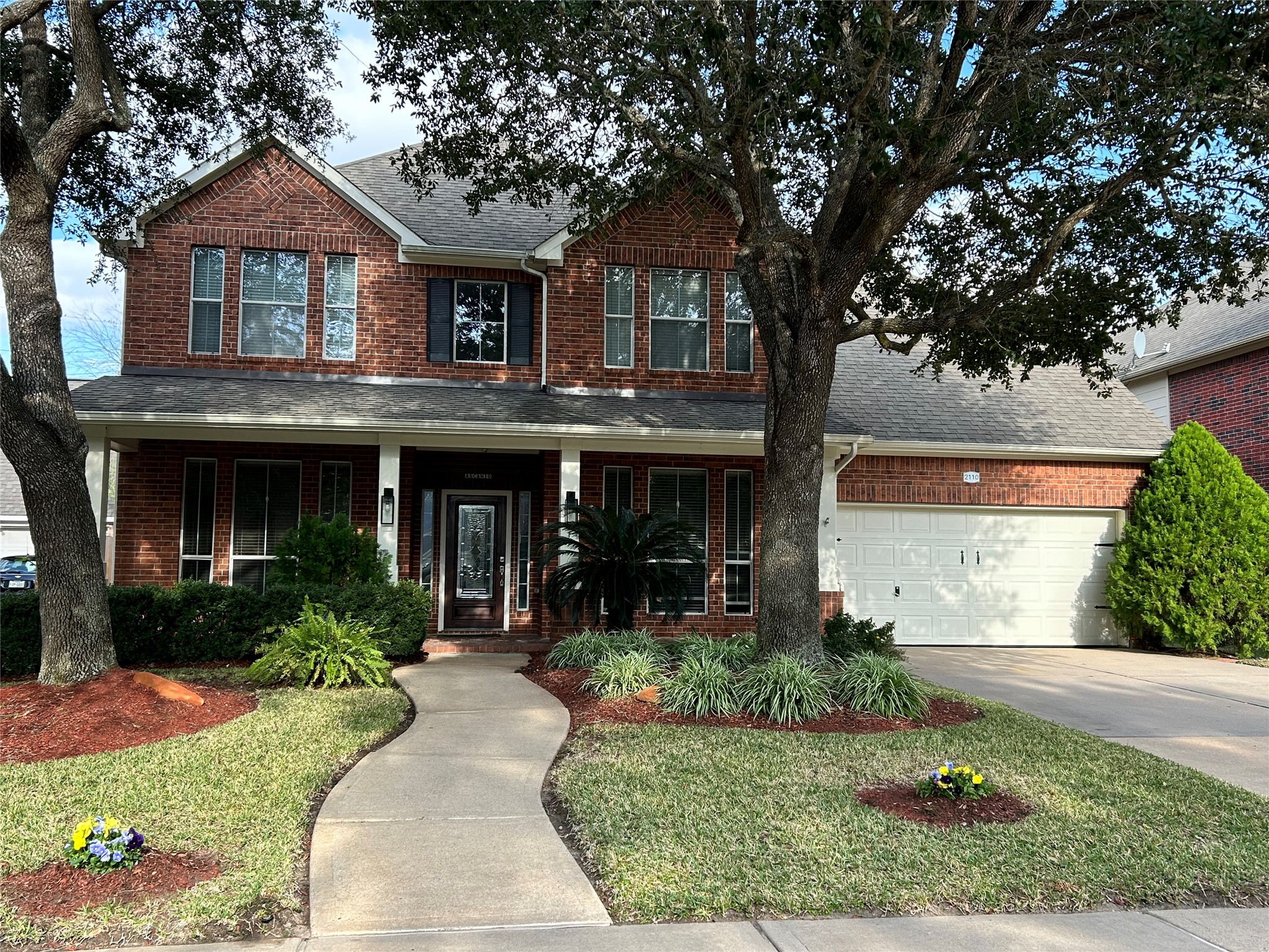 a front view of a house with garden and trees