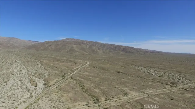 a view of a dry yard with mountains in the background