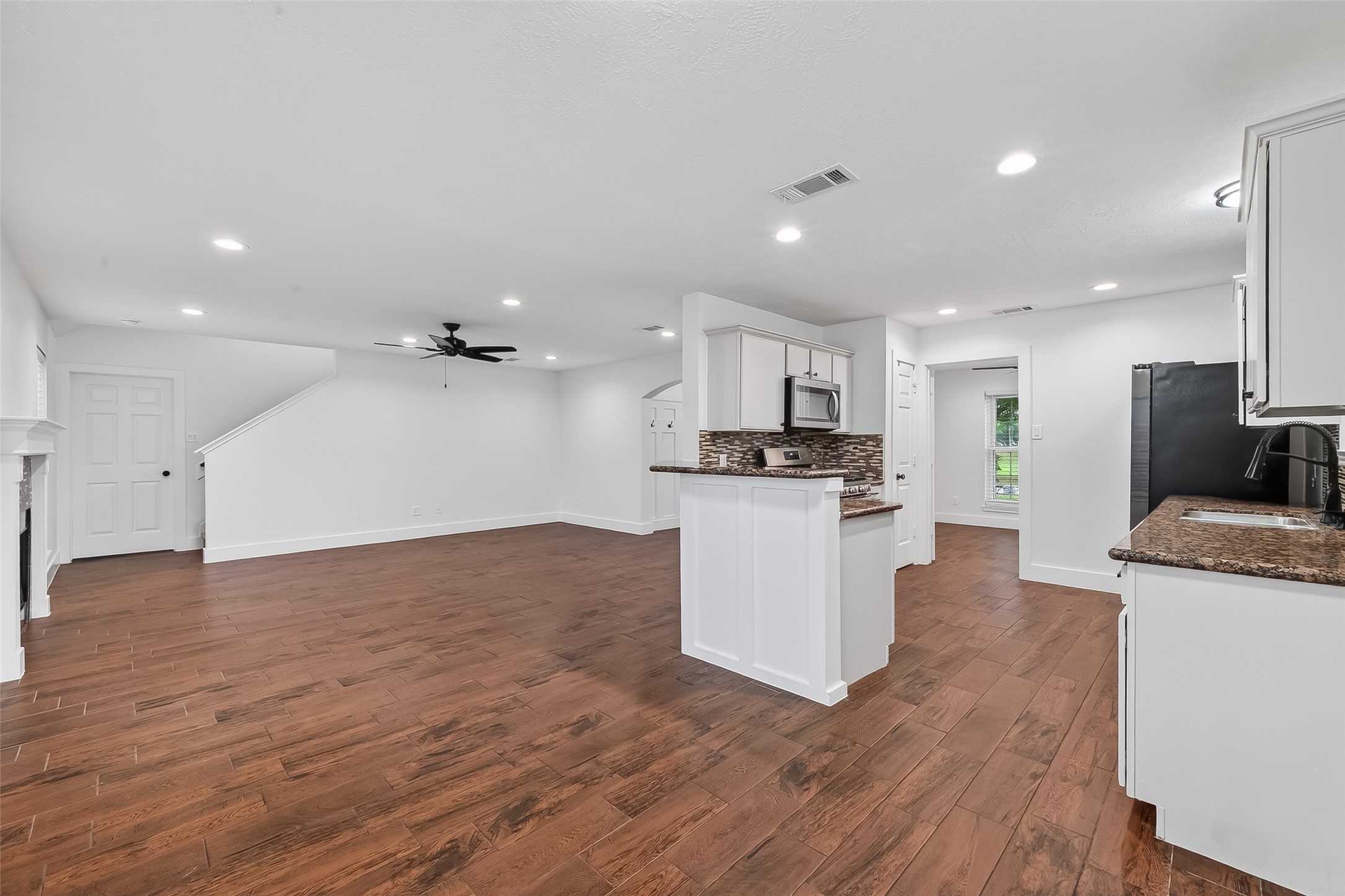 2018 Village Ct Lane Rosenberg, TX 77471 - Photo 19 of 50 a large kitchen with kitchen island a stove a sink a refrigerator and white cabinets with wooden floor