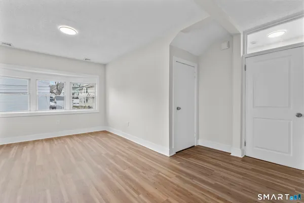 a view of an empty room with wooden floor and a window