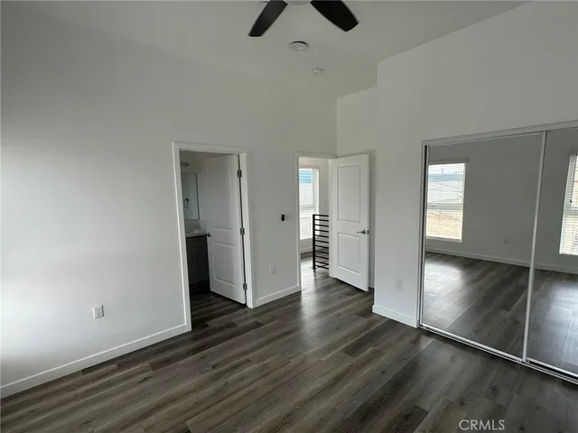 an empty room with wooden floor chandelier fan and windows