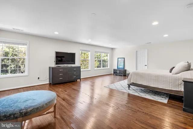 a spacious bedroom with a bed and wooden floor