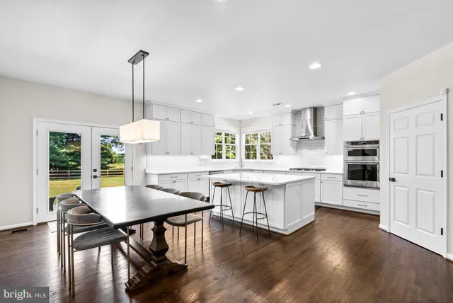 a kitchen with stainless steel appliances granite countertop a table chairs stove and white cabinets