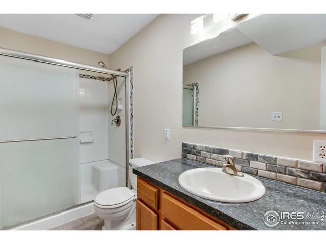 a bathroom with a granite countertop sink toilet a mirror and shower