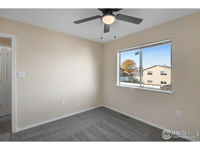 a view of an empty room with wooden floor and a ceiling fan