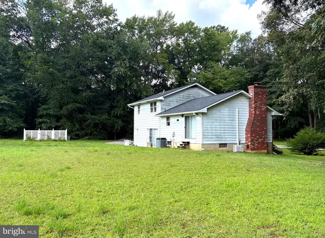 a view of a house with a yard and large trees