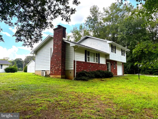 a view of a house with a yard and large trees