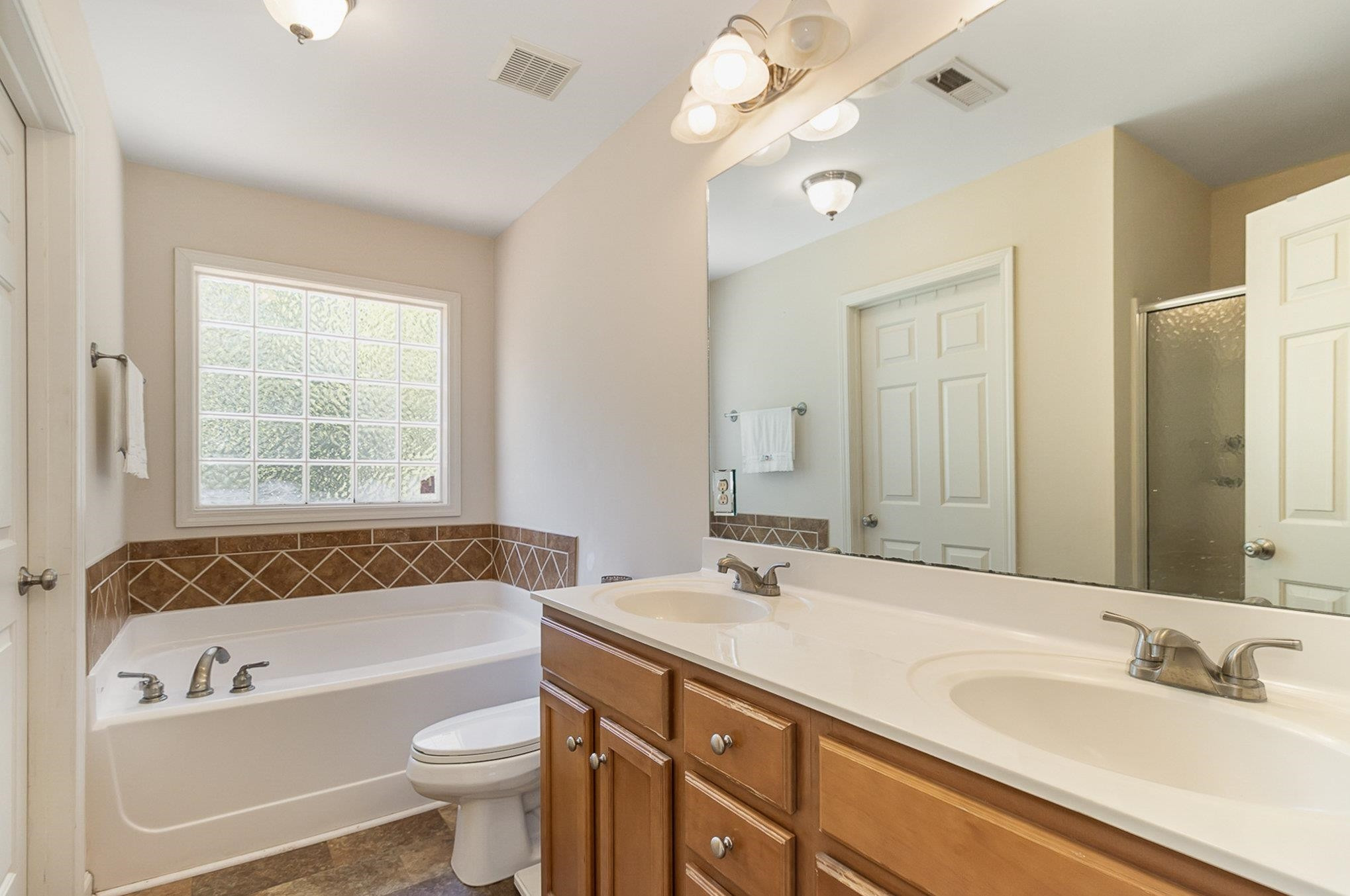 226 Keller Drive Clayton, NC 27520 - Photo 17 of 30 a bathroom with a tub a sink and a large mirror