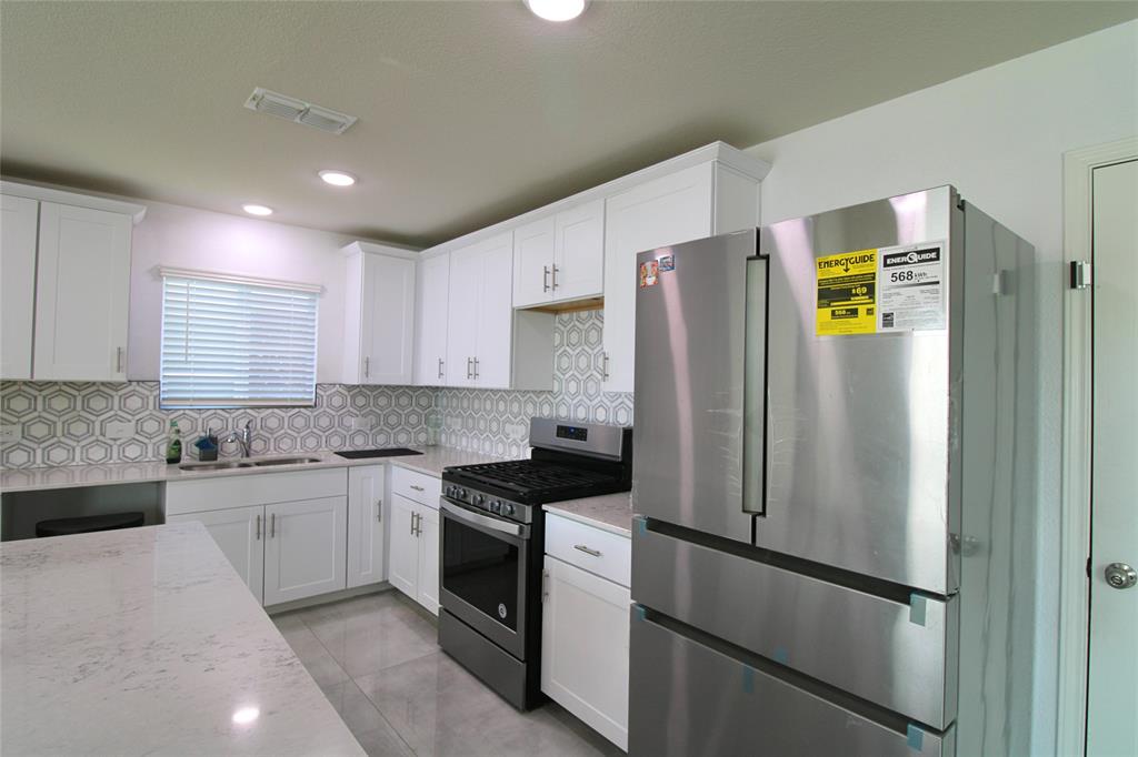 949 Shire Avenue Haslet, TX 76052 - Photo 5 of 22 Kitchen featuring appliances with stainless steel finishes, white cabinets, light stone counters, and recessed lighting