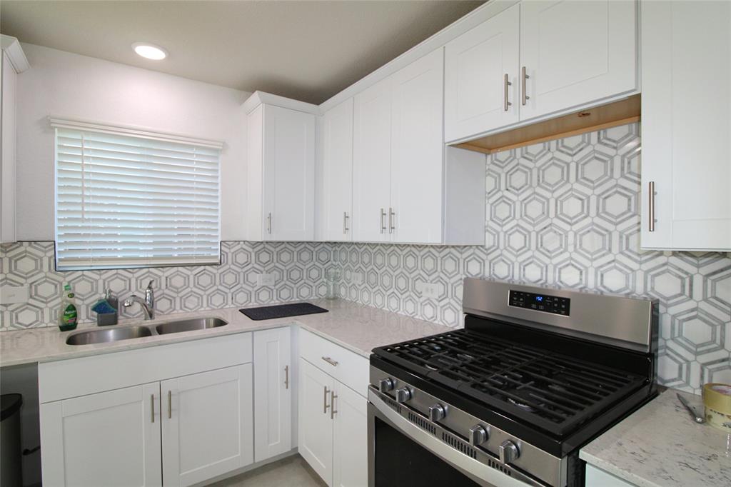949 Shire Avenue Haslet, TX 76052 - Photo 6 of 22 Kitchen with stainless steel range with gas cooktop, light stone countertops, white cabinetry, decorative backsplash, and recessed lighting