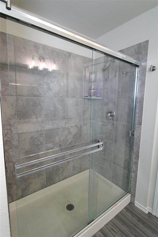949 Shire Avenue Haslet, TX 76052 - Photo 10 of 22 Bathroom featuring a shower stall, wood finished floors, and a textured ceiling
