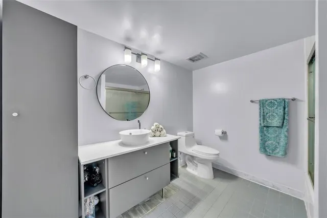 a bathroom with a toilet sink vanity and mirror