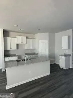 a kitchen with stainless steel appliances granite countertop a sink dishwasher a stove and white cabinets with wooden floor