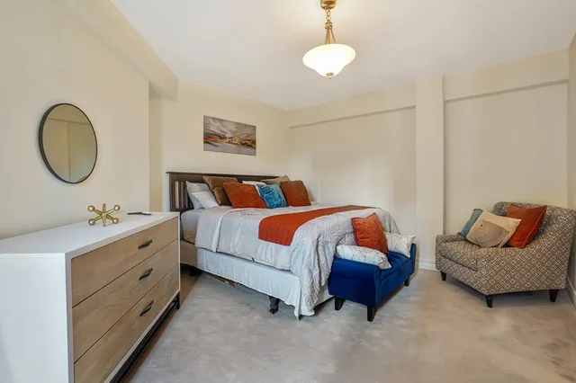 a spacious bedroom with a bed a couch and a potted plant