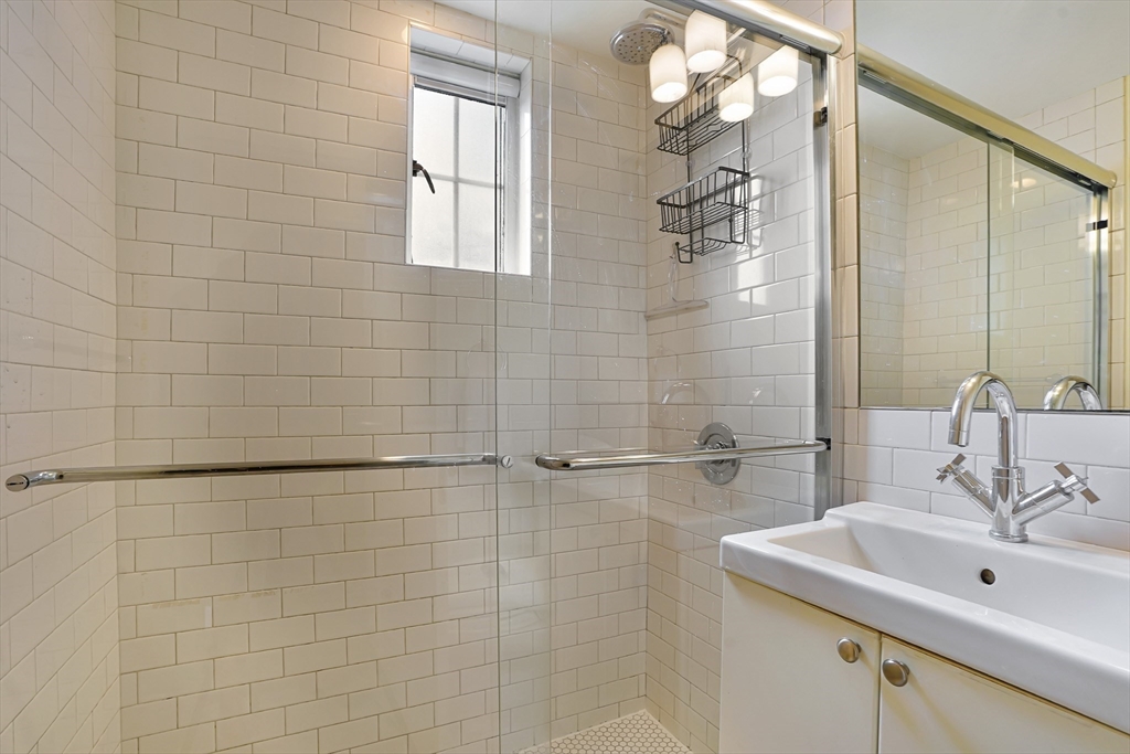 20 Chapel Street, Unit B801 Brookline, MA 02446 - Photo 14 of 27 a bathroom with a sink a mirror and shower