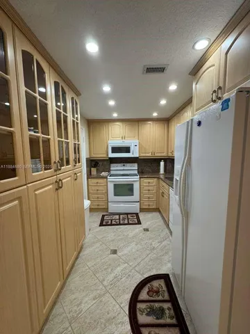 a kitchen with stainless steel appliances granite countertop a refrigerator a stove and a sink with wooden floor