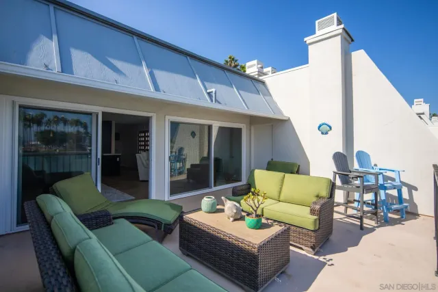 a view of a patio with couches table and chairs with wooden floor and fence
