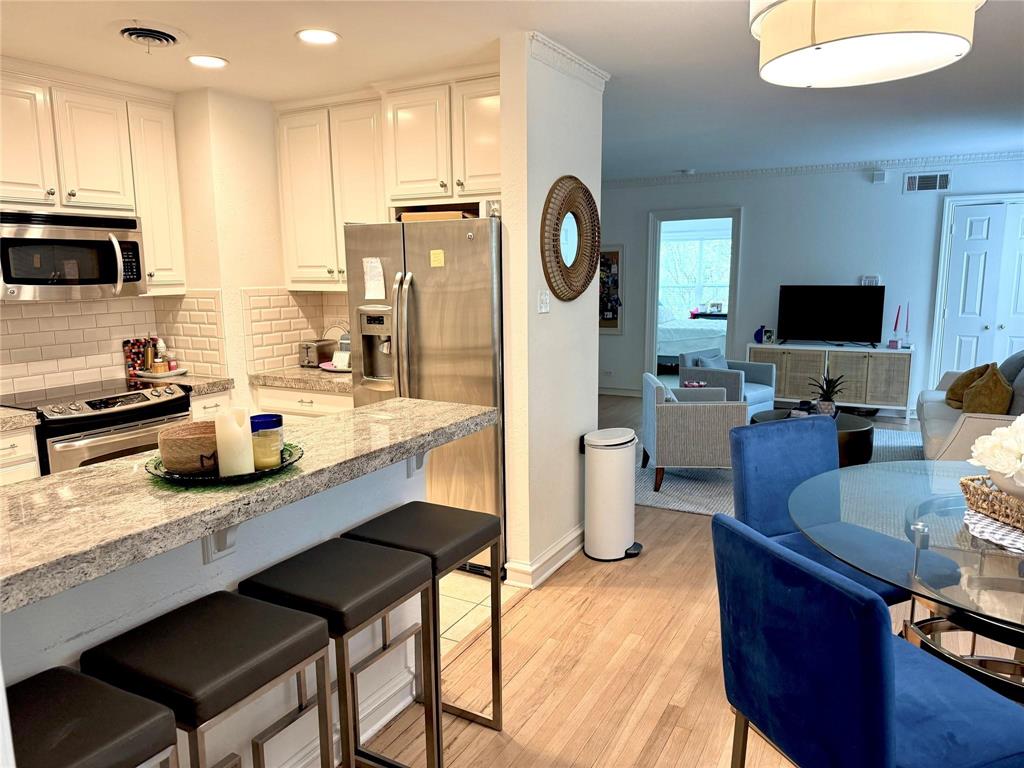4538 Roland Avenue, Unit 4 Highland Park, TX 75219 - Photo 4 of 9 a kitchen with stainless steel appliances granite countertop a stove top oven a refrigerator a sink and chairs