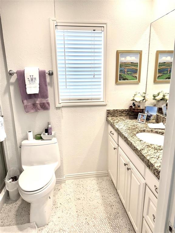 4538 Roland Avenue, Unit 4 Highland Park, TX 75219 - Photo 7 of 9 a bathroom with a granite countertop toilet a sink a mirror and a window