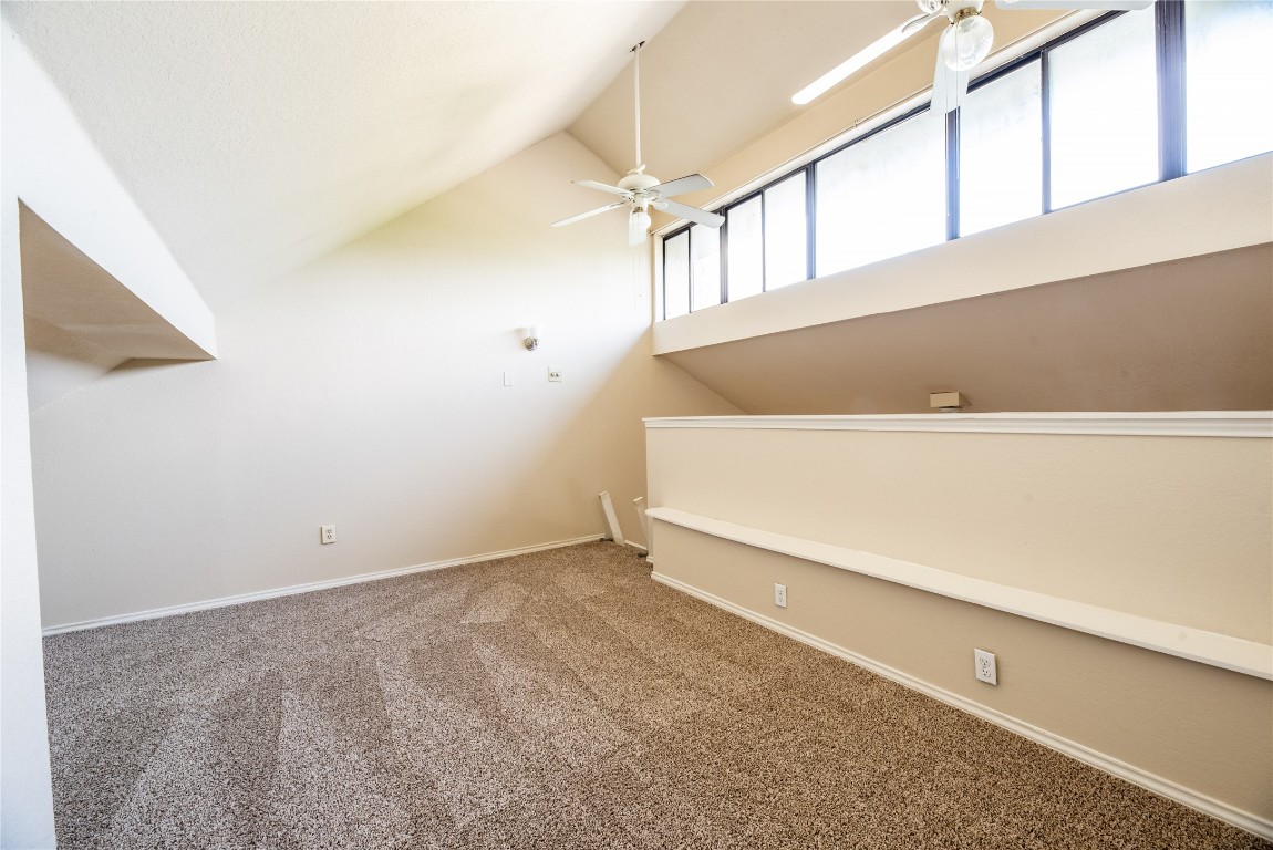601 Nelray Boulevard, Unit 5 Austin, TX 78751 - Photo 10 of 13 Unfurnished living room featuring carpet floors, lofted ceiling, and a ceiling fan