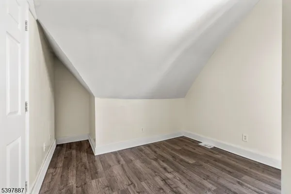 a view of an empty room with wooden floor and closet