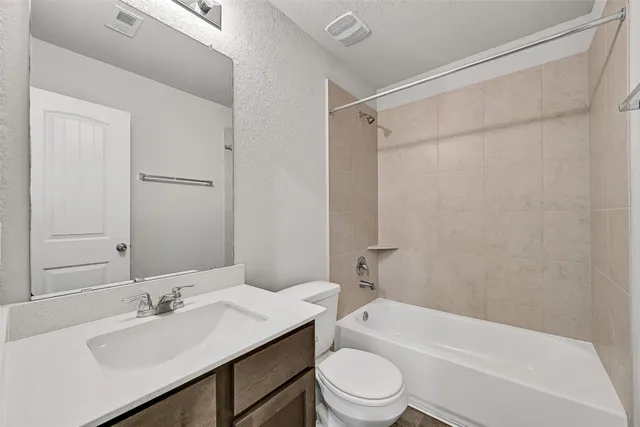 a bathroom with a bathtub shower sink vanity and toilet