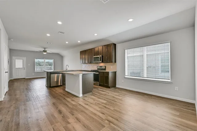 a open kitchen with kitchen island a sink dishwasher stove with wooden floors and a fireplace