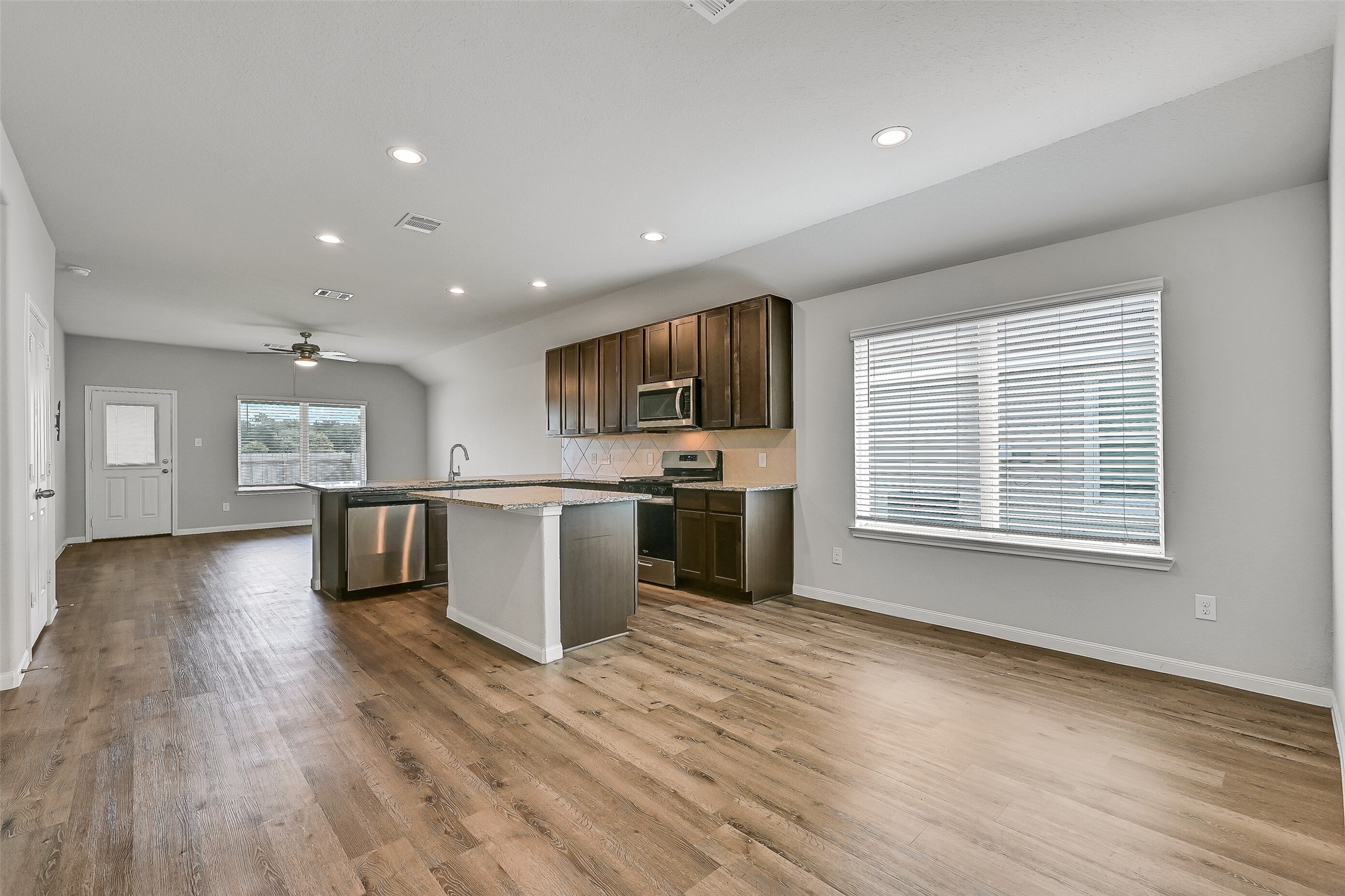 5407 James Michael Drive Rosharon, TX 77583 - Photo 6 of 32 a open kitchen with kitchen island a sink dishwasher stove with wooden floors and a fireplace
