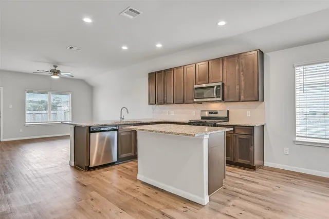 a kitchen with granite countertop wooden floors and stainless steel appliances