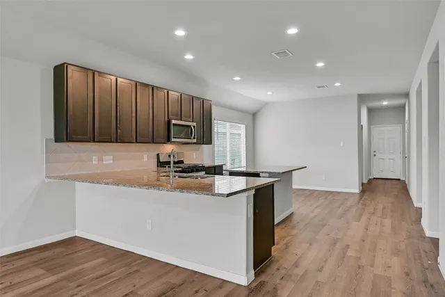 a kitchen with granite countertop a stove top oven and cabinets